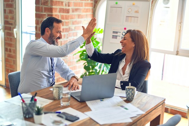 Two people in business dress high-fiving.