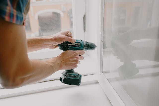 A person using a drill to fix a doorframe.